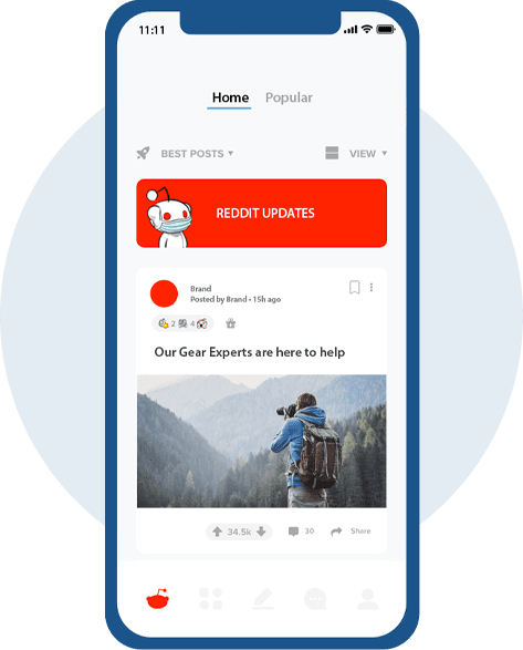 custom-ppc-campaigns Mobile phone screen showing a Reddit feed. A Reddit ad displays a picture of a person holding a camera and taking a picture of an evergreen forest. The ad caption reads Our Gear Experts are here to help.
